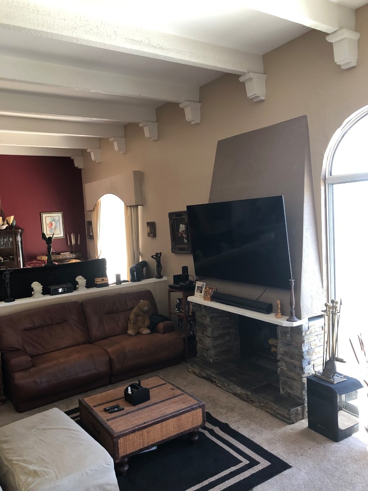 Photo of a large modern open concept living room in Phoenix with a music area, beige walls, carpet, a stone fireplace surround, a wall-mounted tv and beige floor.