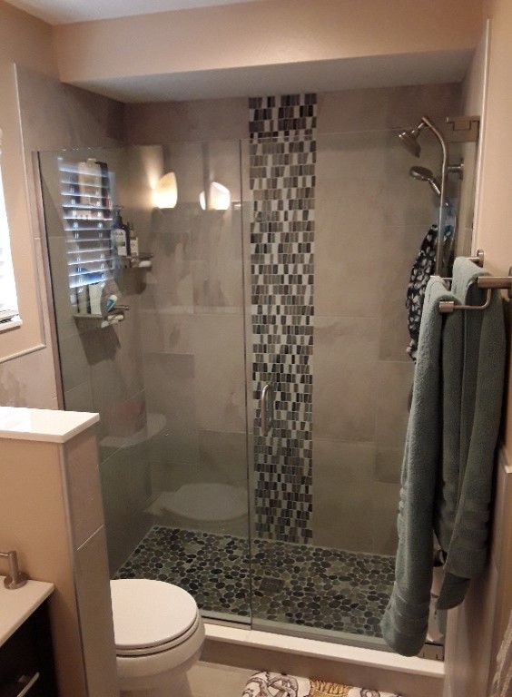 This is an example of a transitional master bathroom in Tampa with flat-panel cabinets, dark wood cabinets, a double shower, a two-piece toilet, multi-coloured tile, glass tile, beige walls, porcelain floors, an integrated sink, engineered quartz benchtops, white floor and a hinged shower door.