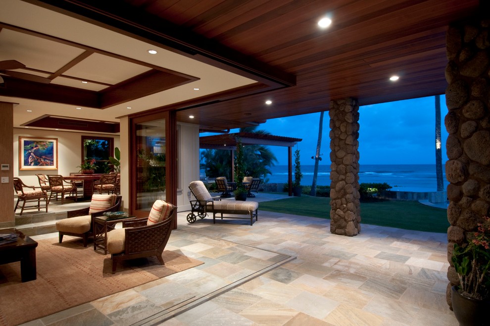 Photo of a large tropical backyard patio in Hawaii with a roof extension.