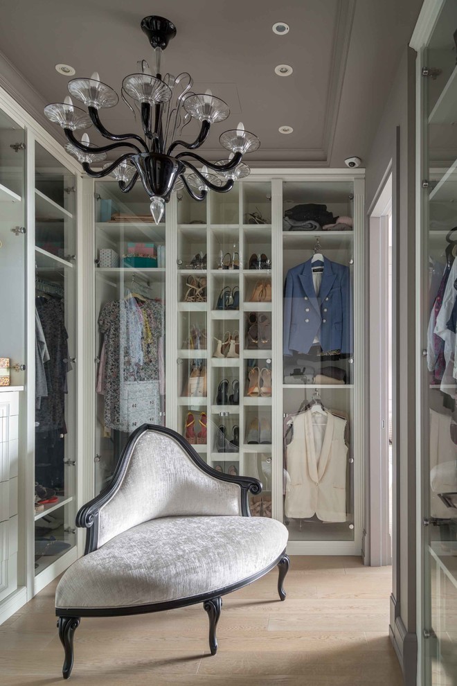 Design ideas for a transitional walk-in wardrobe in Moscow with glass-front cabinets, light hardwood floors and beige floor.