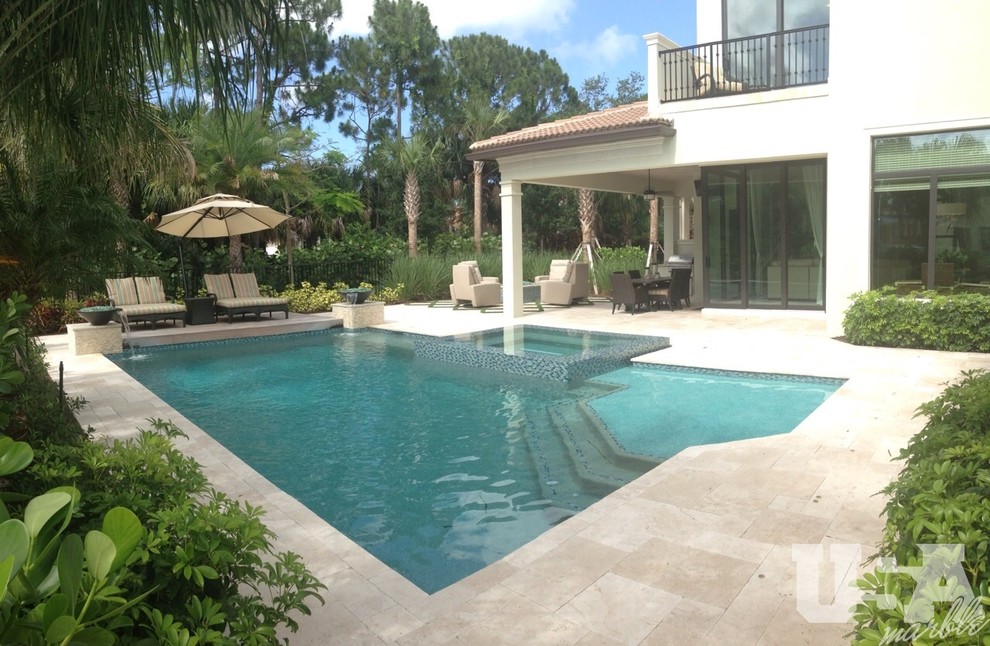 Large contemporary backyard rectangular aboveground pool in Miami with a water feature and natural stone pavers.