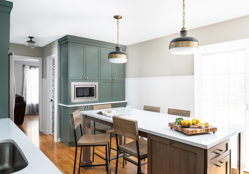 Mid-sized transitional u-shaped separate kitchen in Chicago with an undermount sink, shaker cabinets, green cabinets, quartz benchtops, white splashback, cement tile splashback, stainless steel appliances, light hardwood floors, with island and white benchtop.