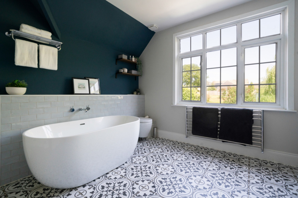 Идея дизайна: большая главная, серо-белая ванная комната в современном стиле с фасадами в стиле шейкер, синими фасадами, отдельно стоящей ванной, двойным душем, инсталляцией, серой плиткой, керамической плиткой, полом из керамической плитки, раковиной с пьедесталом, столешницей из гранита, серым полом, открытым душем, белой столешницей, акцентной стеной, тумбой под две раковины и напольной тумбой