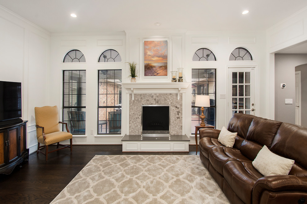 Photo of a mid-sized transitional open concept living room in Dallas with grey walls, medium hardwood floors, a standard fireplace, a tile fireplace surround, a freestanding tv and brown floor.