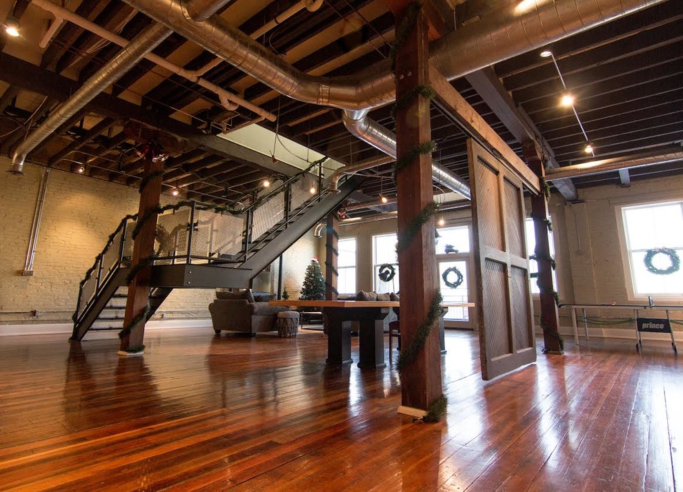 Expansive industrial walk-out basement in Orange County with white walls, brown floor and dark hardwood floors.