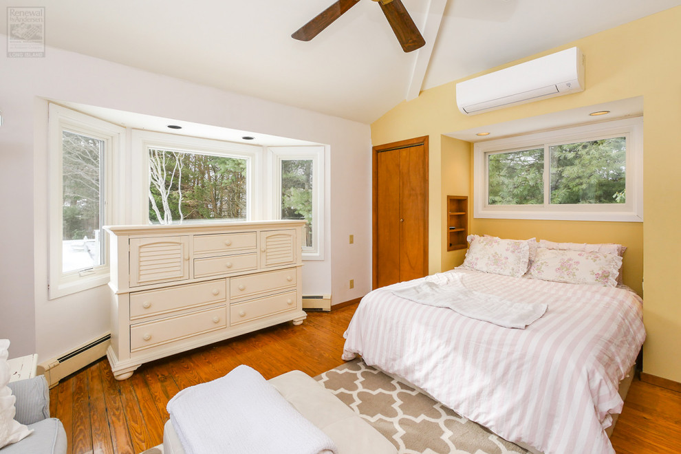 Modelo de dormitorio principal y abovedado grande con paredes multicolor, suelo de madera en tonos medios y suelo multicolor