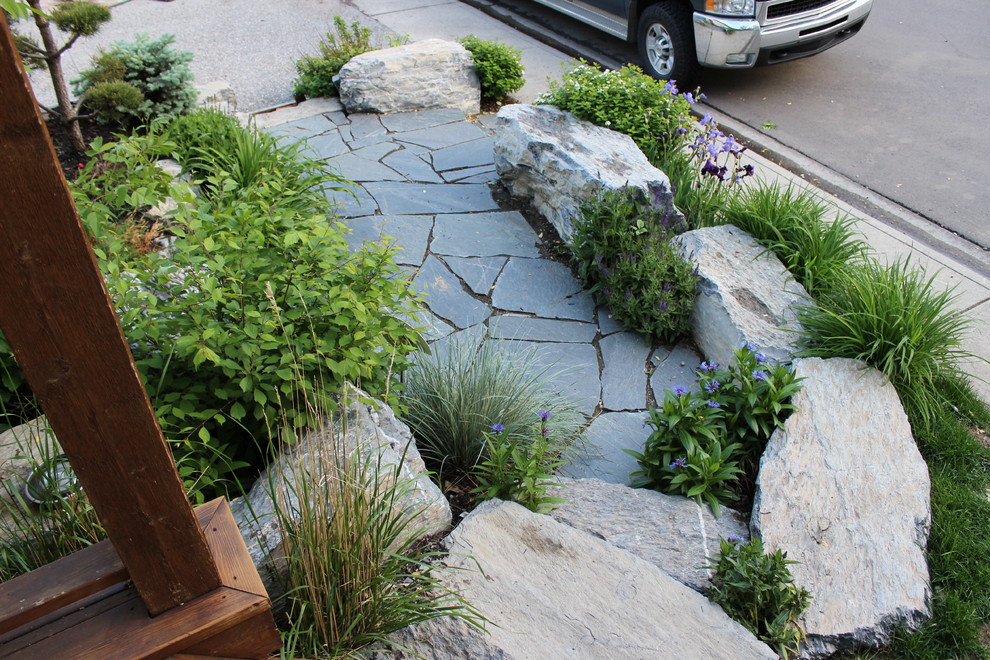 Design ideas for a large traditional backyard partial sun garden for summer in Calgary with natural stone pavers.