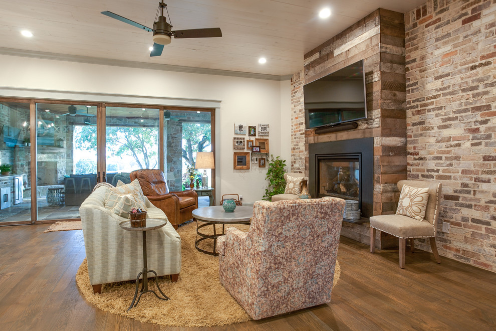 Photo of a mid-sized country formal enclosed living room in Dallas with white walls, dark hardwood floors, a standard fireplace, a brick fireplace surround and a wall-mounted tv.