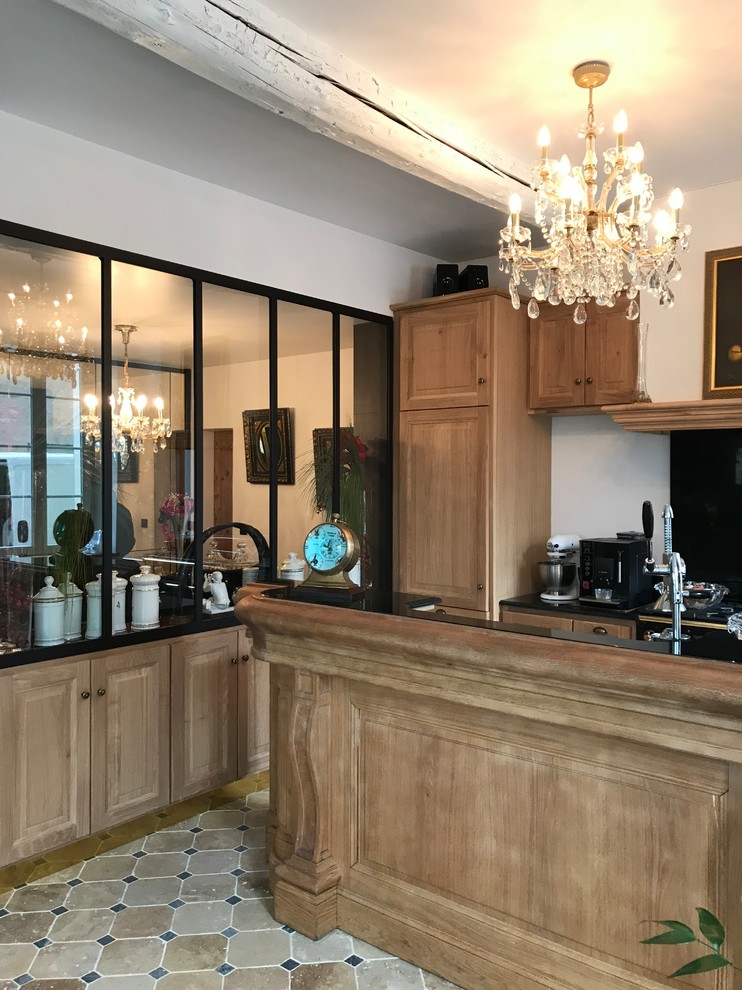 Design ideas for a mid-sized traditional single-wall open plan kitchen in Marseille with an undermount sink, travertine floors, beige floor, beaded inset cabinets, light wood cabinets, black splashback, black appliances and black benchtop.
