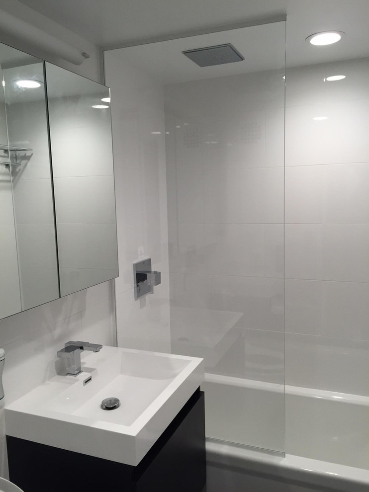 This is an example of a mid-sized modern 3/4 bathroom in New York with flat-panel cabinets, black cabinets, an alcove tub, a shower/bathtub combo, white tile, glass tile, an integrated sink and an open shower.