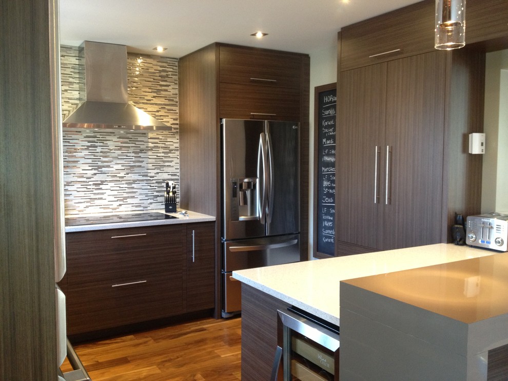 Contemporary kitchen in Montreal with dark wood cabinets, quartzite benchtops, grey splashback, mosaic tile splashback, stainless steel appliances, medium hardwood floors and with island.