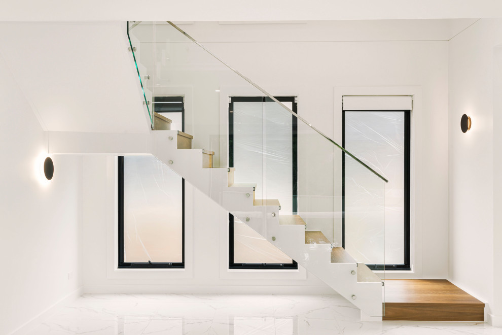 Modern wood l-shaped staircase in Sydney with glass risers and metal railing.