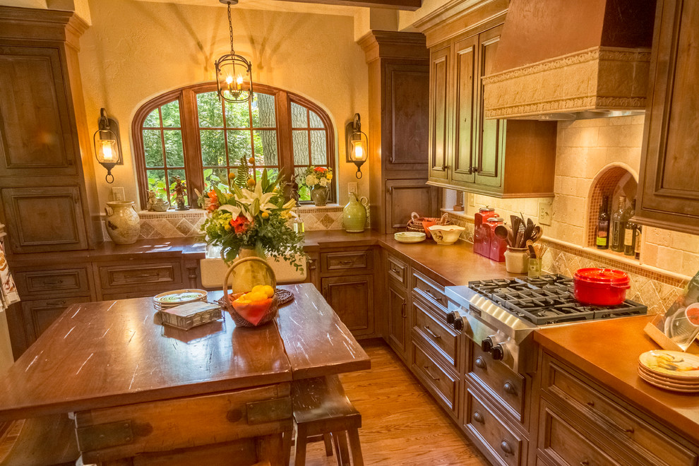 This is an example of a small mediterranean l-shaped eat-in kitchen in St Louis with a farmhouse sink, shaker cabinets, medium wood cabinets, concrete benchtops, beige splashback, stone tile splashback, stainless steel appliances, medium hardwood floors and with island.