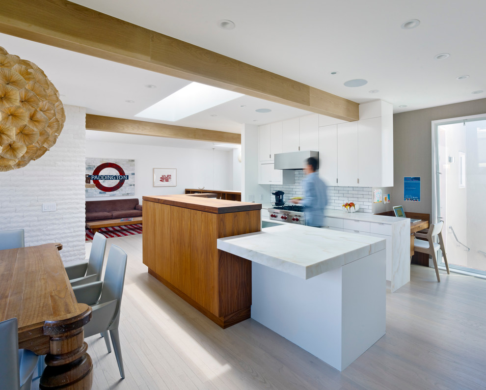 This is an example of a modern eat-in kitchen in San Francisco with marble benchtops, flat-panel cabinets, white cabinets, white splashback and subway tile splashback.