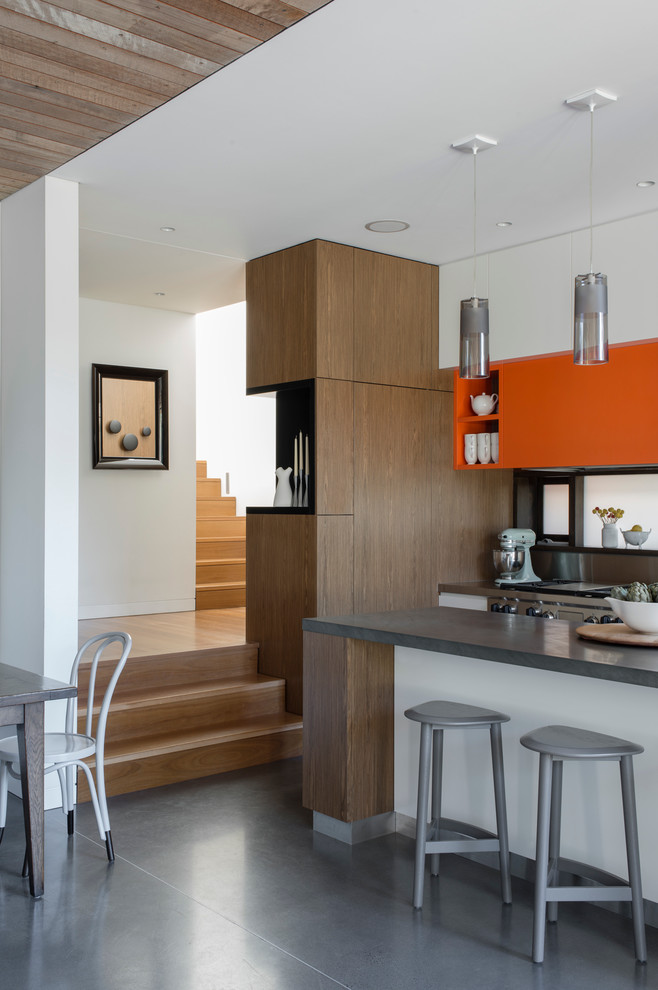 Photo of a mid-sized contemporary l-shaped eat-in kitchen in Sydney with an integrated sink, flat-panel cabinets, medium wood cabinets, granite benchtops, stainless steel appliances, concrete floors, with island and metallic splashback.