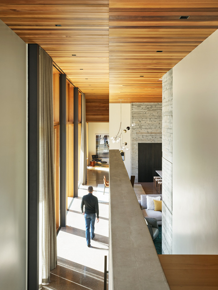 Cette image montre un couloir minimaliste avec sol en béton ciré et un plafond en bois.
