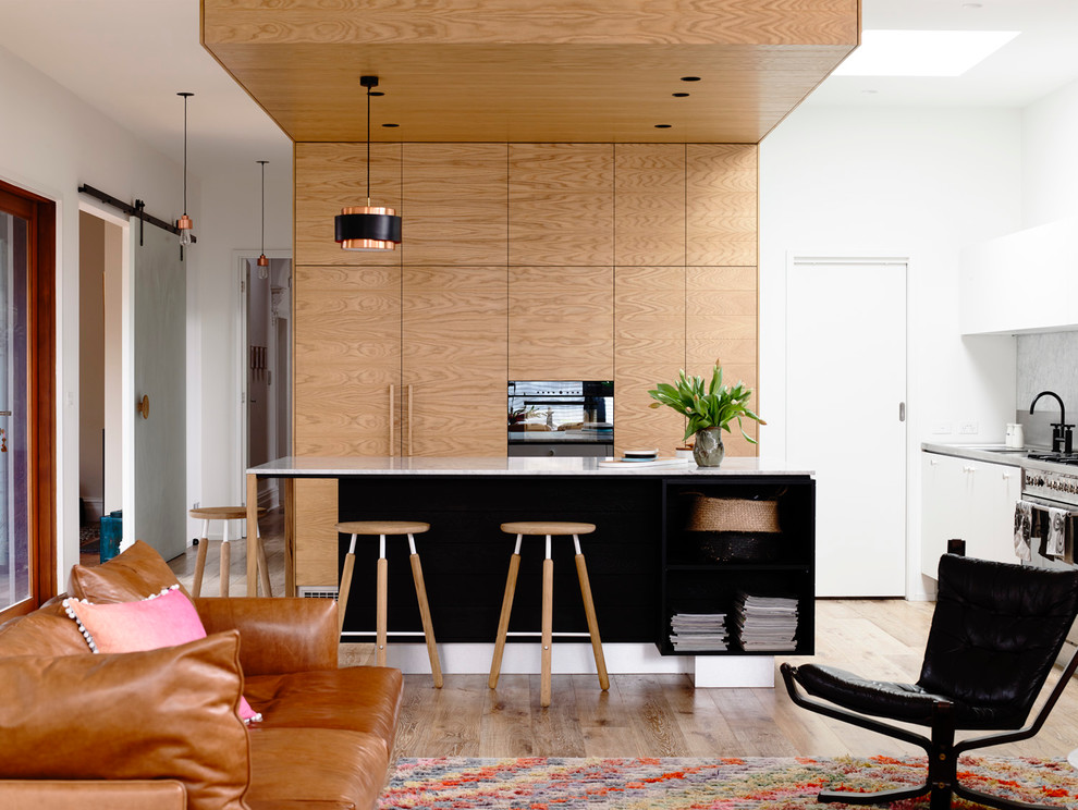 This is an example of a mid-sized contemporary l-shaped open plan kitchen in Melbourne with flat-panel cabinets, medium wood cabinets, stainless steel benchtops, metallic splashback, medium hardwood floors and with island.