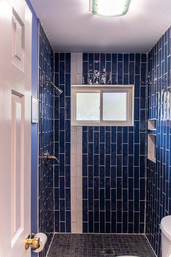 This is an example of a small transitional 3/4 bathroom with shaker cabinets, white cabinets, an open shower, a one-piece toilet, blue tile, ceramic tile, blue walls, wood-look tile, an integrated sink, engineered quartz benchtops, grey floor, an open shower, white benchtops, a single vanity and a freestanding vanity.