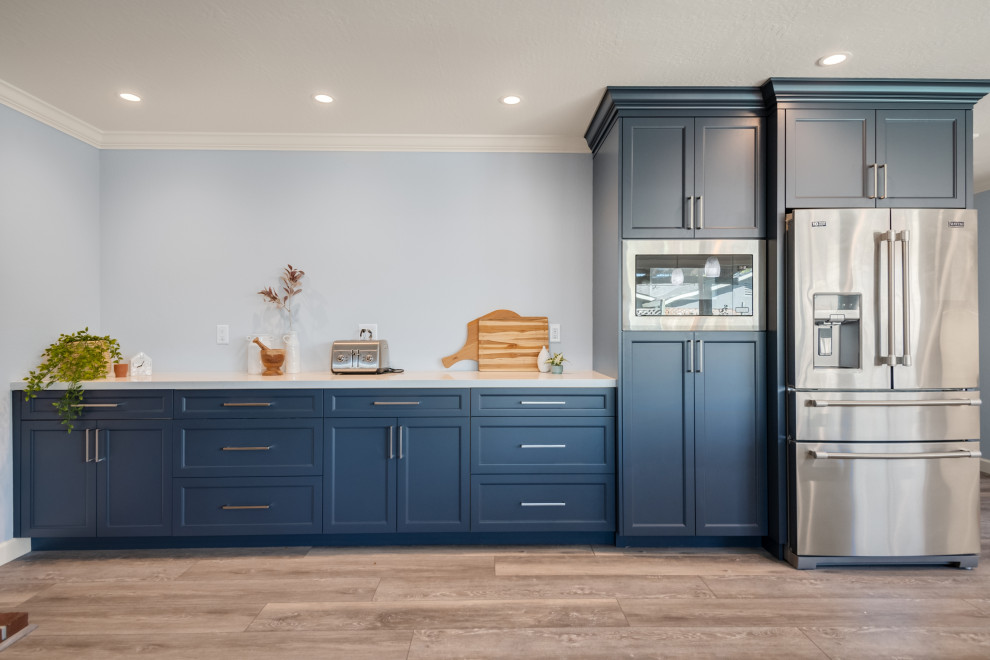 Inspiration for a mid-sized contemporary l-shaped eat-in kitchen in San Francisco with shaker cabinets, blue cabinets, quartzite benchtops, blue splashback, stainless steel appliances, vinyl floors, a peninsula, brown floor and white benchtop.