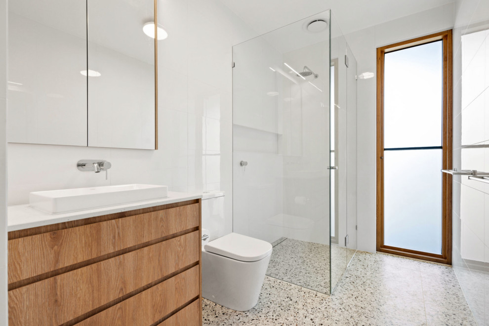 Photo of a midcentury master bathroom in Geelong with furniture-like cabinets, a corner shower, a one-piece toilet, white tile, porcelain tile, white walls, porcelain floors, a hinged shower door, a niche, a single vanity and a built-in vanity.