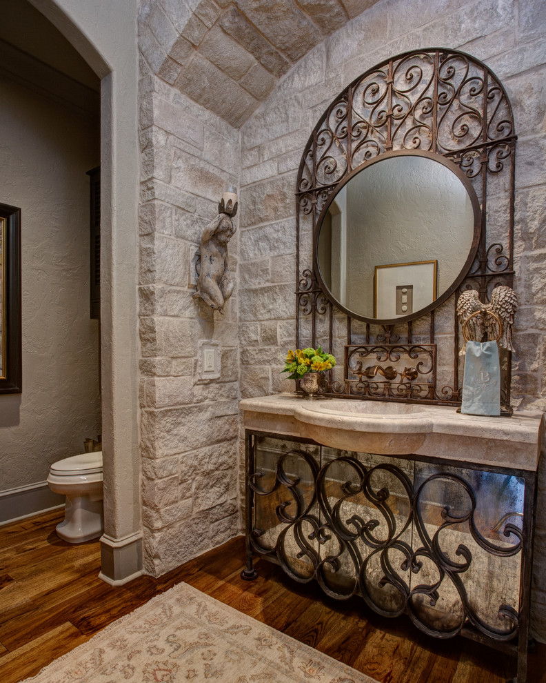 Inspiration for a mid-sized traditional 3/4 bathroom in Little Rock with glass-front cabinets, beige cabinets, a two-piece toilet, beige tile, stone tile, beige walls, dark hardwood floors, an integrated sink, soapstone benchtops and brown floor.