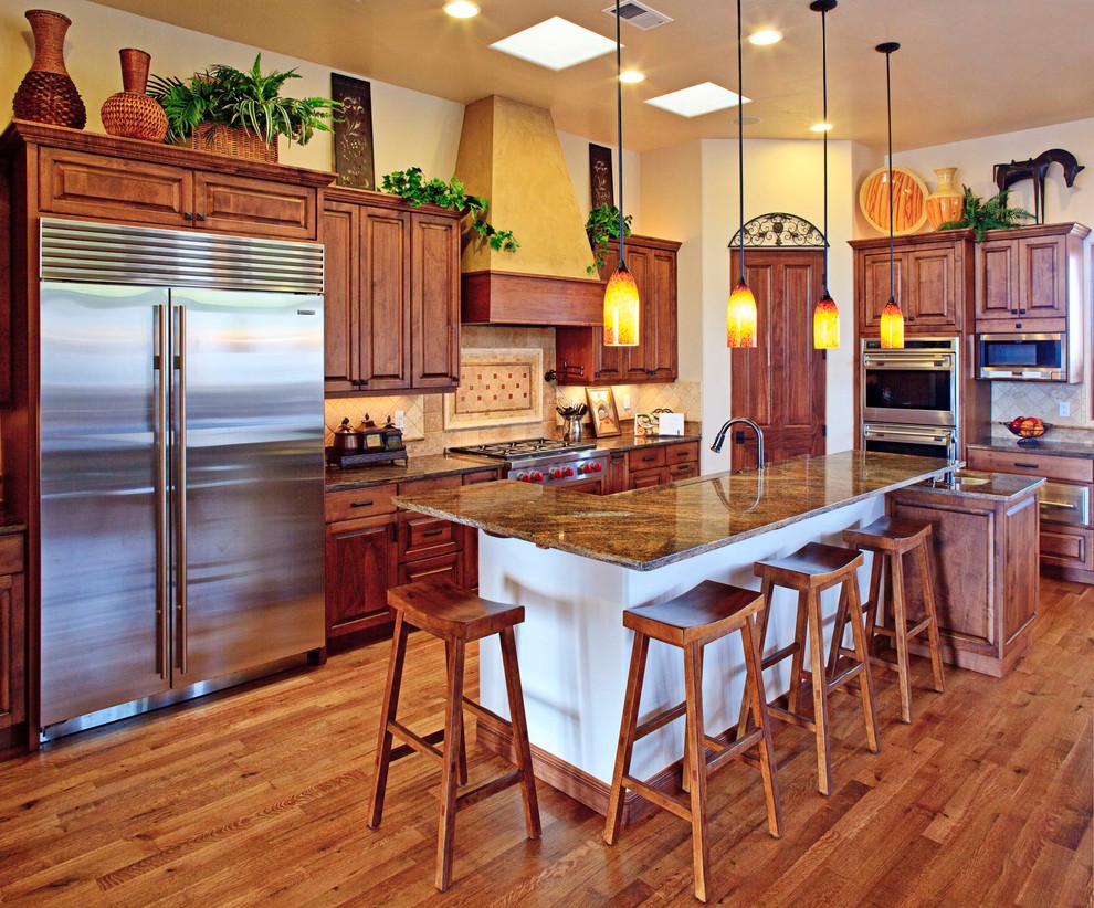 Mid-sized eclectic l-shaped kitchen in Albuquerque with raised-panel cabinets, dark wood cabinets, granite benchtops, beige splashback, ceramic splashback, stainless steel appliances, medium hardwood floors, with island and brown floor.
