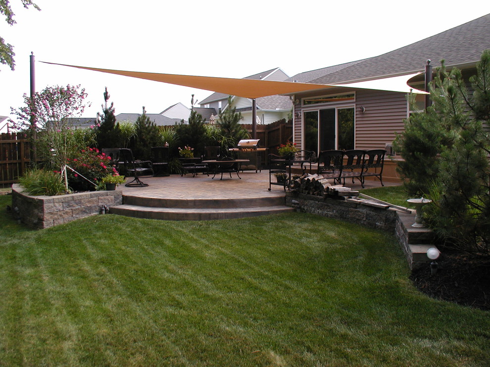 Photo of a large traditional backyard patio in Cleveland with an outdoor kitchen, concrete pavers and an awning.