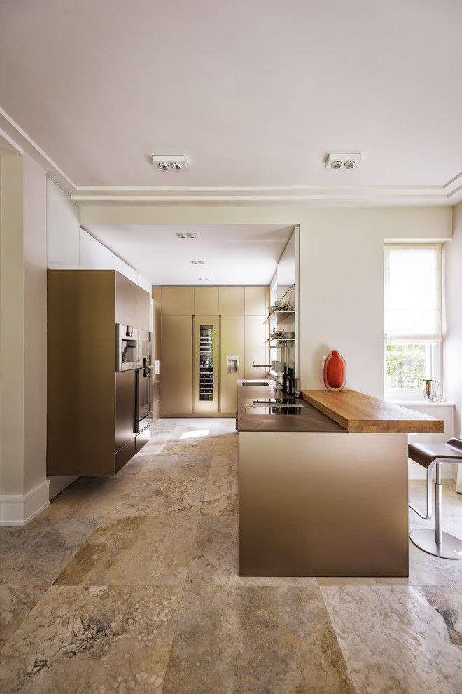 Design ideas for a large u-shaped open plan kitchen in Berlin with an undermount sink, flat-panel cabinets, beige cabinets, limestone benchtops, white splashback, glass sheet splashback, stainless steel appliances, limestone floors, a peninsula, beige floor and brown benchtop.