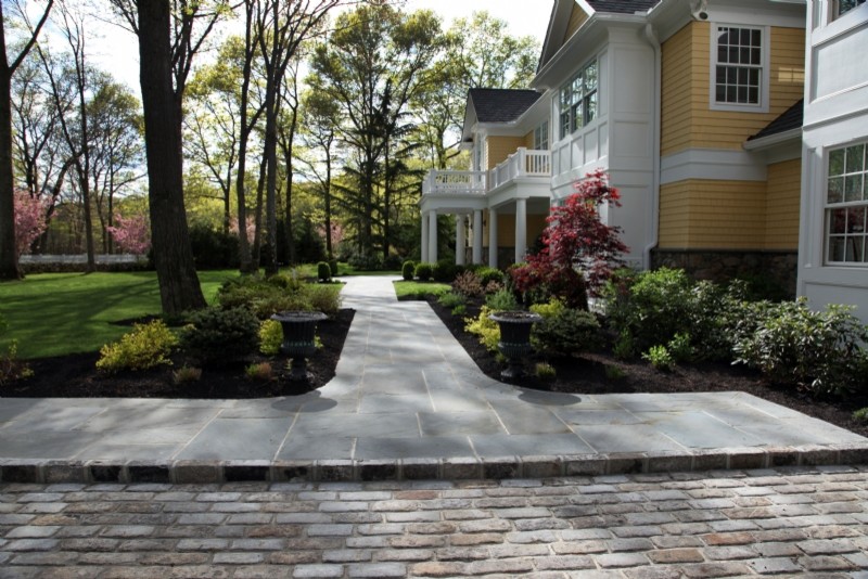 Photo of an expansive traditional front yard shaded driveway in New York with natural stone pavers.