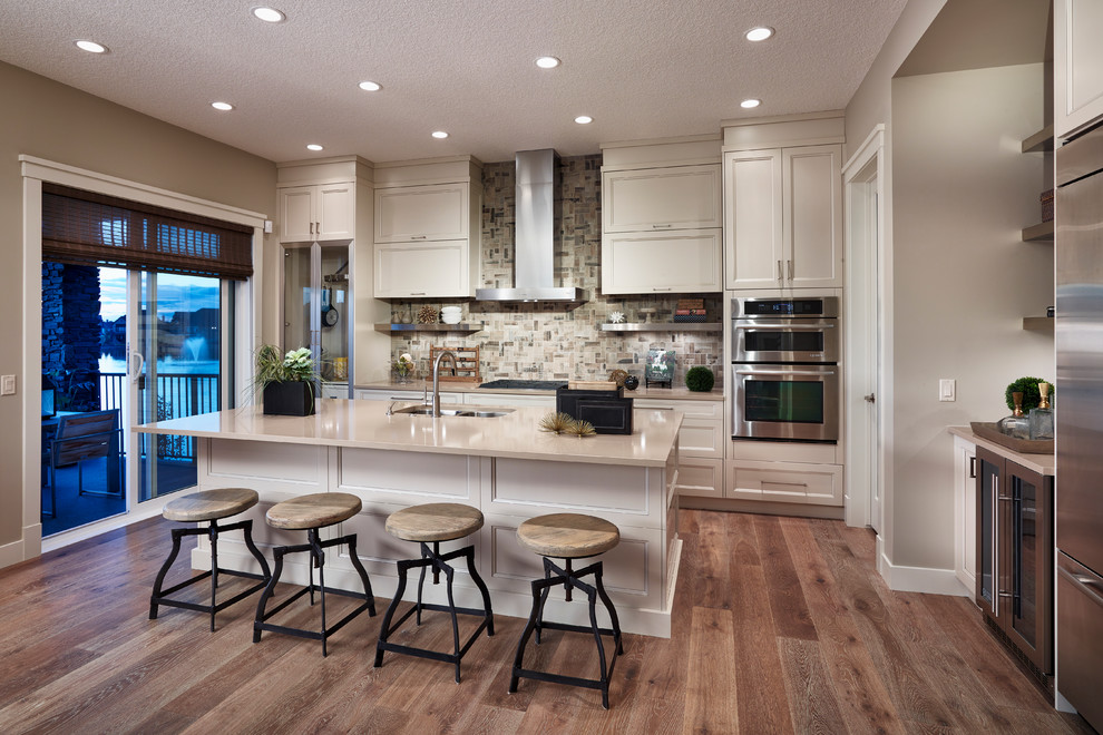 Open concept kitchen - mid-sized transitional l-shaped medium tone wood floor open concept kitchen idea in Calgary with an undermount sink, recessed-panel cabinets, white cabinets, quartzite countertops, gray backsplash, ceramic backsplash, stainless steel appliances and an island