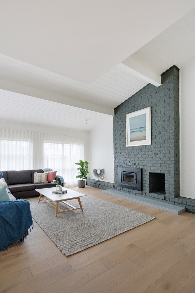 Photo of a large contemporary open concept living room in Sydney with white walls, limestone floors, a standard fireplace, a brick fireplace surround and beige floor.