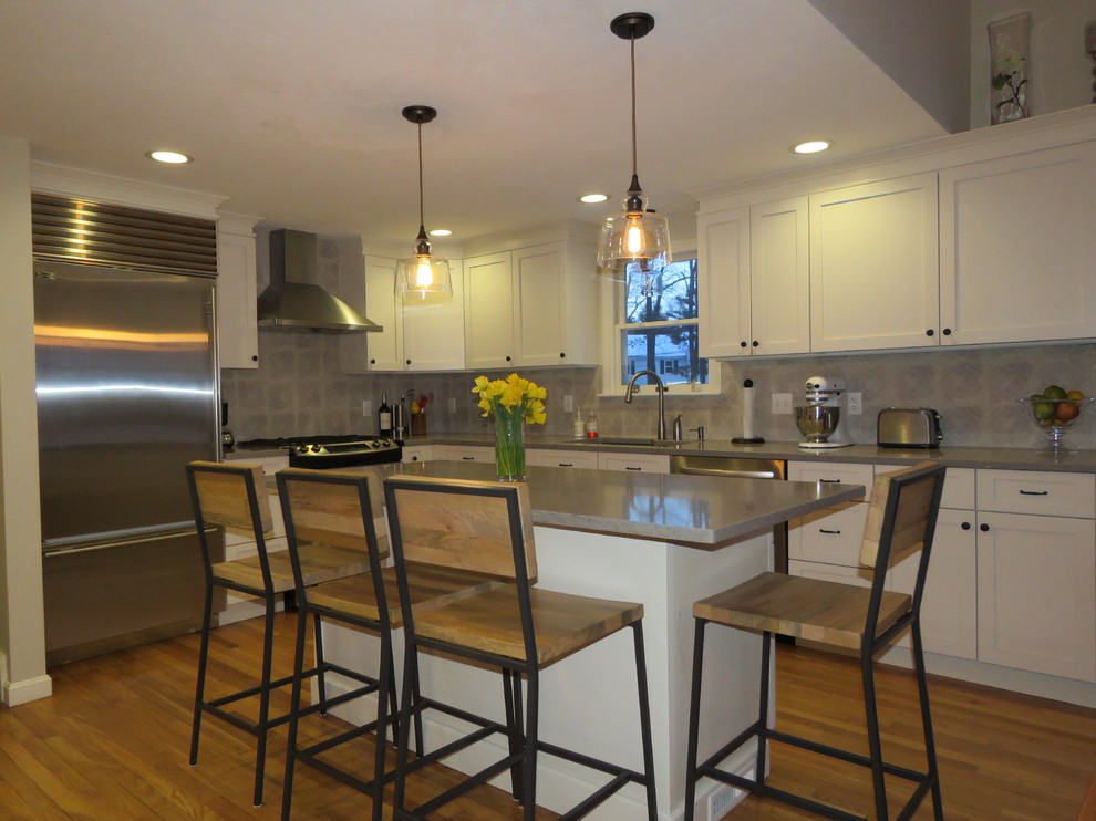 Example of a large transitional l-shaped medium tone wood floor open concept kitchen design in Boston with an undermount sink, shaker cabinets, white cabinets, quartz countertops, gray backsplash, stainless steel appliances and an island
