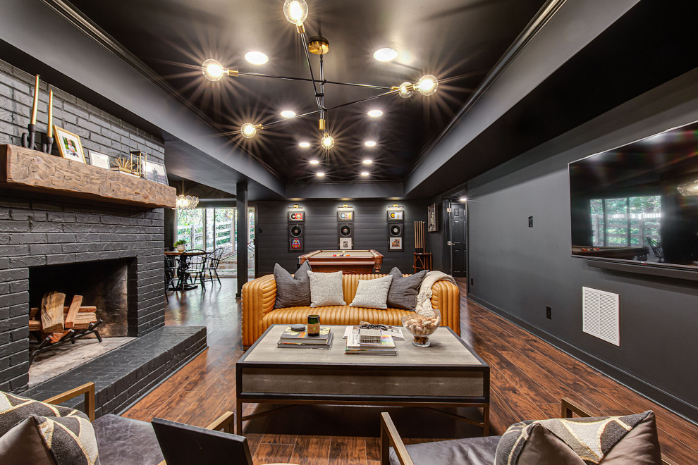 Design ideas for a large contemporary walk-out basement in Atlanta with a home bar, black walls, vinyl flooring, a standard fireplace, a brick fireplace surround, brown floors and tongue and groove walls.