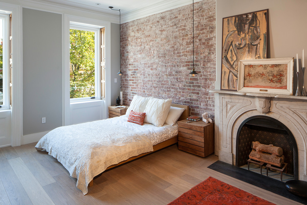Transitional master bedroom in New York with grey walls, light hardwood floors and a standard fireplace.