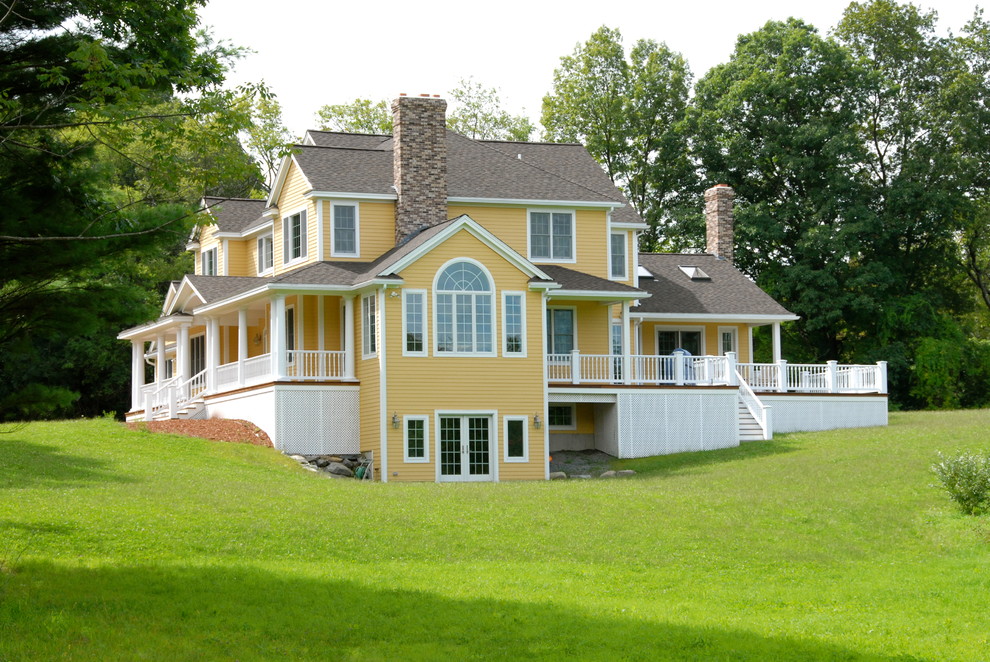 Photo of a large traditional two-storey yellow exterior in Boston with concrete fiberboard siding and a gable roof.