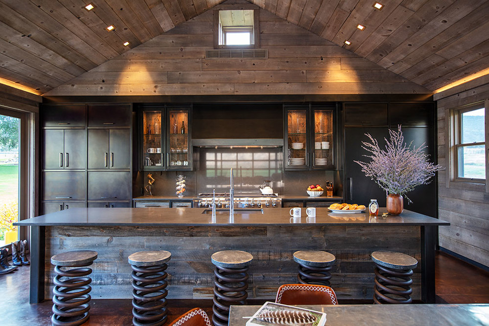 Inspiration for a country galley eat-in kitchen in Denver with an undermount sink, flat-panel cabinets, black cabinets, grey splashback, stone slab splashback, stainless steel appliances, with island, brown floor and grey benchtop.