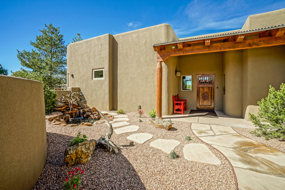 This is an example of a mid-sized one-storey adobe beige house exterior in Albuquerque with a flat roof.