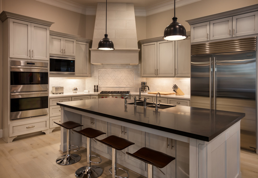 Large transitional u-shaped light wood floor open concept kitchen photo in Houston with a drop-in sink, shaker cabinets, black cabinets, granite countertops, white backsplash, porcelain backsplash, stainless steel appliances and an island