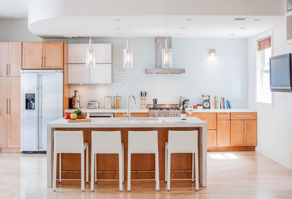 Inspiration for a transitional light wood floor kitchen remodel in Boston with shaker cabinets, medium tone wood cabinets, white backsplash, subway tile backsplash, stainless steel appliances and an island