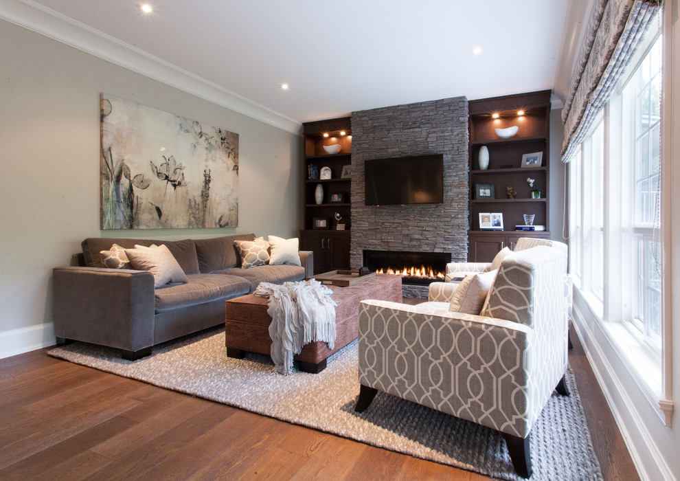 This is an example of a large traditional family room in Vancouver with grey walls, medium hardwood floors, a ribbon fireplace, a stone fireplace surround and a wall-mounted tv.