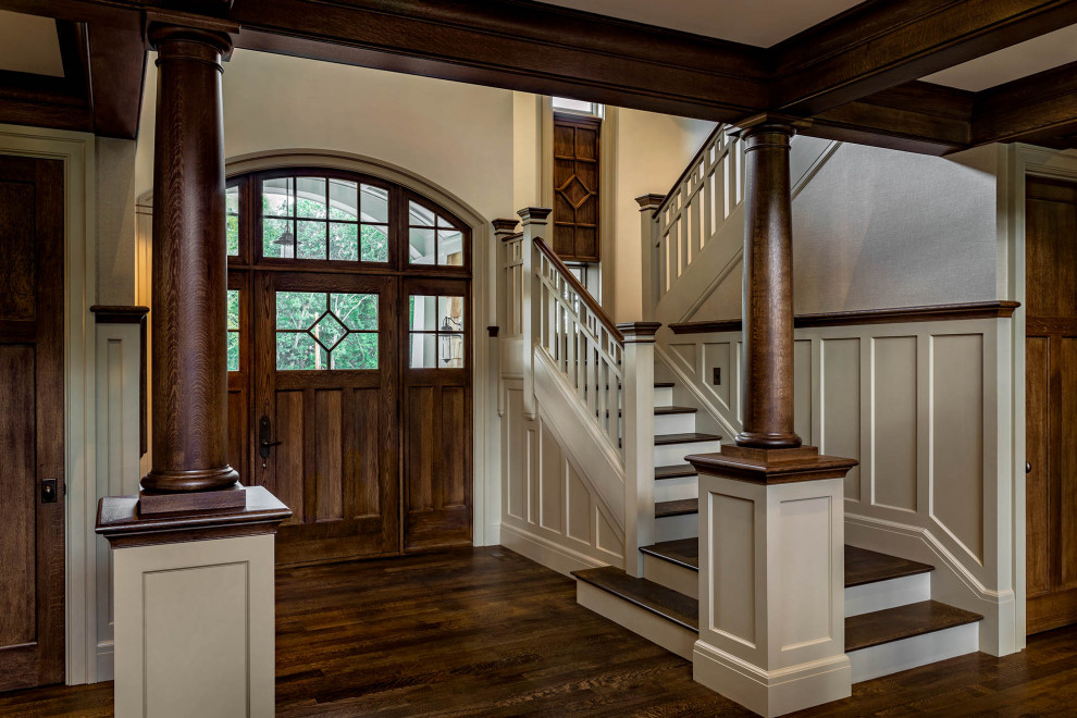 This is an example of a large arts and crafts foyer in Boston with white walls, dark hardwood floors, a single front door, a dark wood front door, brown floor, coffered and decorative wall panelling.