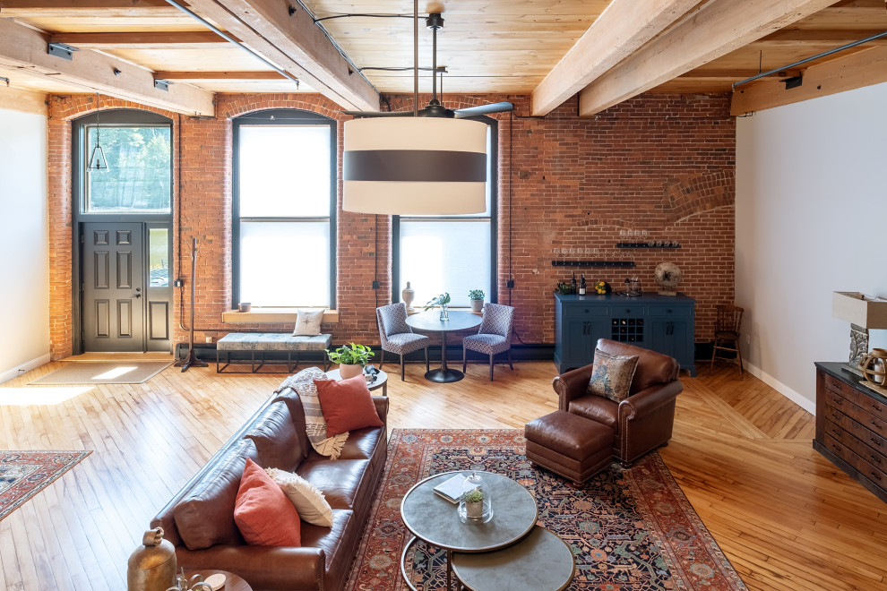 Inspiration for an expansive industrial open concept living room in Boston with light hardwood floors and exposed beam.