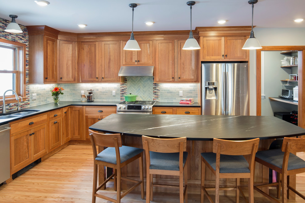 Photo of a large arts and crafts l-shaped separate kitchen in Minneapolis with an undermount sink, shaker cabinets, light wood cabinets, soapstone benchtops, grey splashback, ceramic splashback, stainless steel appliances, light hardwood floors and with island.