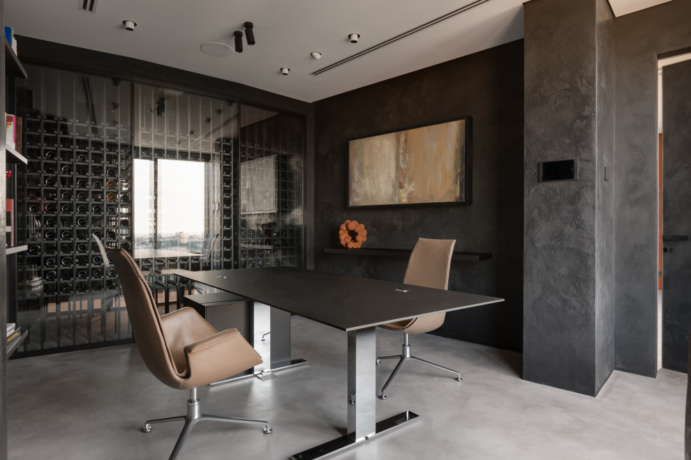 Cette photo montre un bureau atelier industriel de taille moyenne avec un mur noir, sol en béton ciré, un bureau indépendant, un sol gris et boiseries.