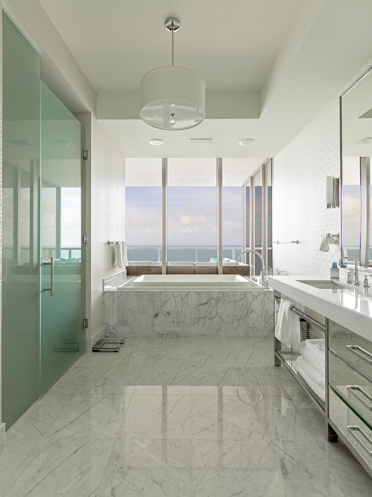 Design ideas for a large contemporary master bathroom in Miami with a drop-in tub, a curbless shower, white tile, marble floors, an undermount sink, flat-panel cabinets, white walls, a hinged shower door and marble.