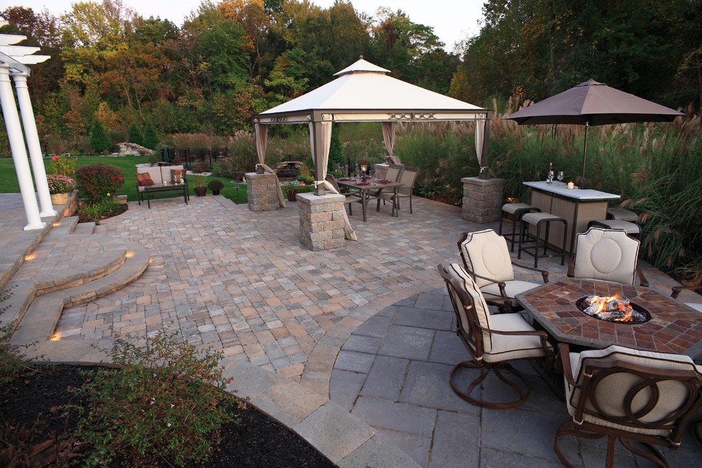 This is an example of a large traditional backyard patio in Philadelphia with concrete pavers, a gazebo/cabana and a fire feature.