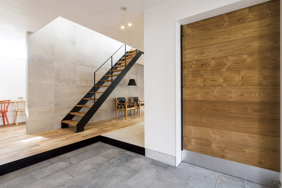 This is an example of an asian entry hall in Other with white walls, granite floors, a sliding front door, a medium wood front door, grey floor, timber and planked wall panelling.