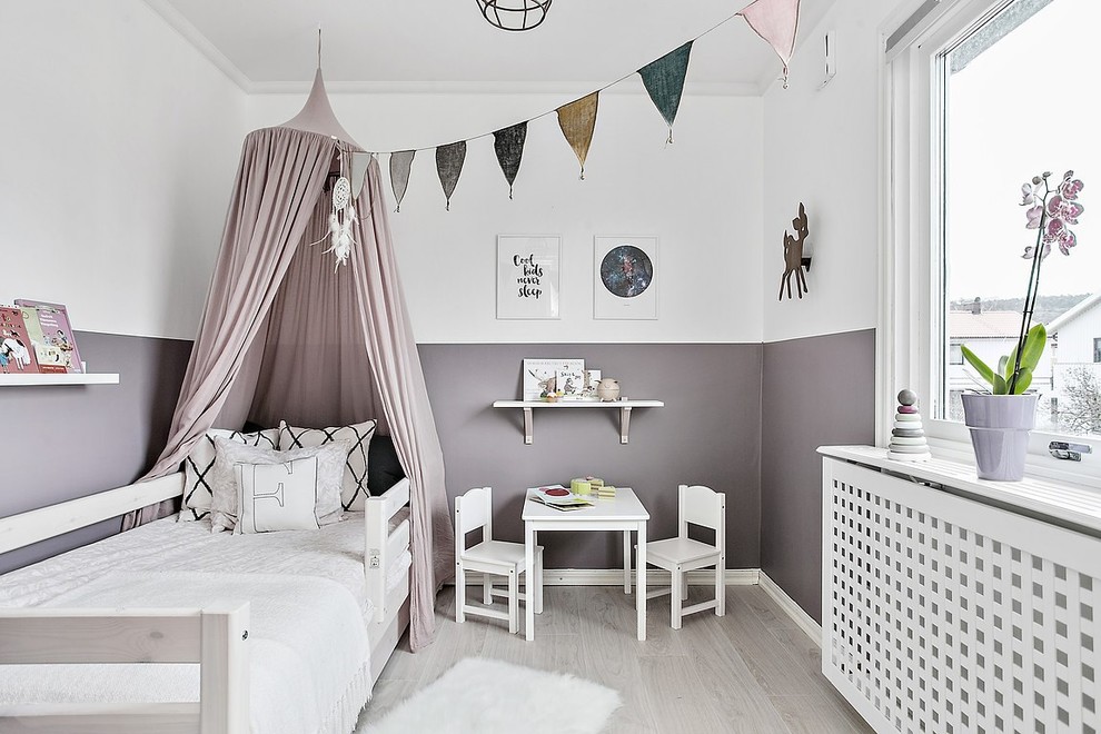 Photo of a scandinavian kids' bedroom for girls in Gothenburg with purple walls, light hardwood floors and grey floor.