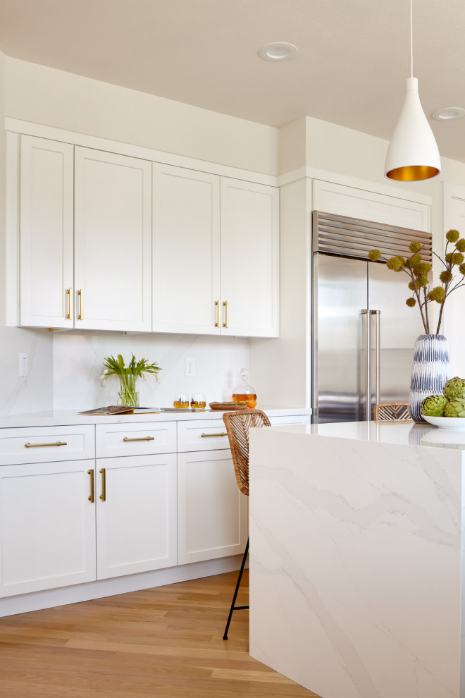 Inredning av ett retro mellanstort vit vitt kök, med en enkel diskho, skåp i shakerstil, blå skåp, bänkskiva i kvarts, vitt stänkskydd, rostfria vitvaror, ljust trägolv, en köksö och brunt golv