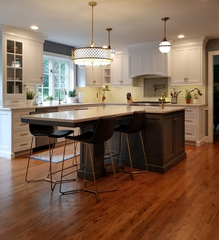 Inspiration for a mid-sized transitional l-shaped kitchen in Philadelphia with an undermount sink, beaded inset cabinets, white cabinets, quartz benchtops, white splashback, subway tile splashback, stainless steel appliances, medium hardwood floors, with island, brown floor and white benchtop.